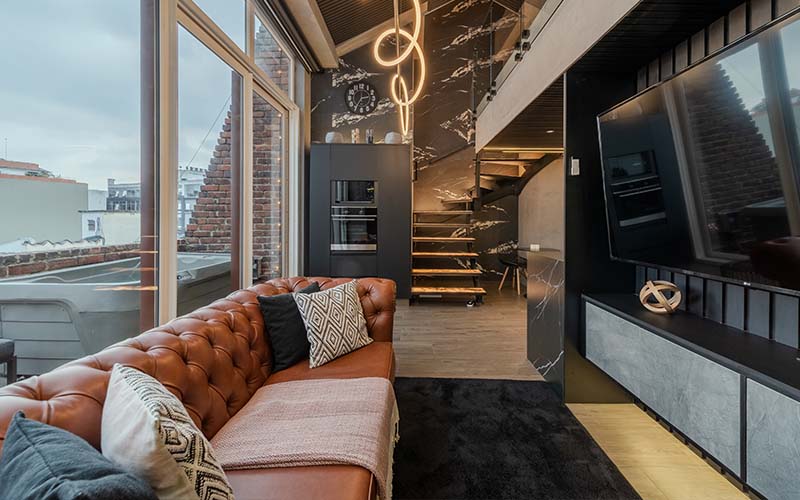 Living room with large TV and stairs leading to loft-style bedroom